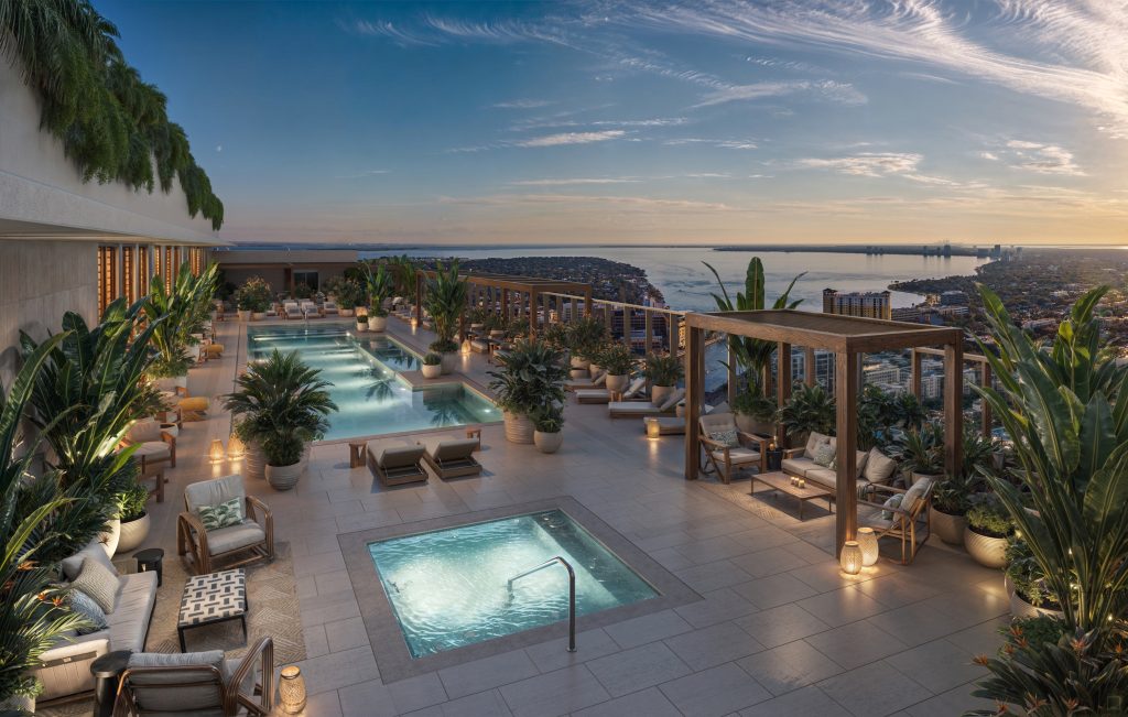 Rooftop pool deck at The Pendry Residences in downtown Tampa at twilight, featuring an infinity pool, plunge pool, modern lounge seating, lush landscaping, and panoramic views of Tampa Bay and the city skyline.